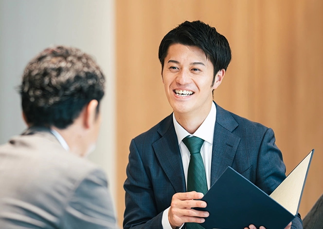 笑顔で打ち合わせをする男性社員