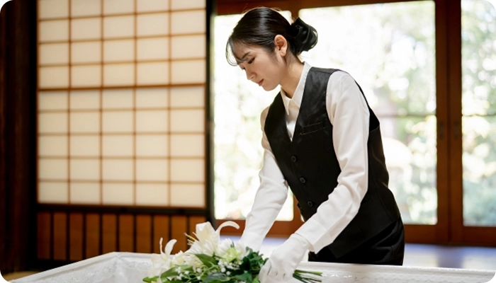 棺に花を添える女性スタッフ